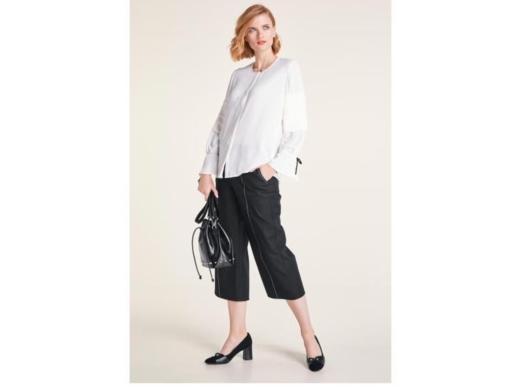 Die Kombination aus weißer Bluse und Culotte ist derzeit angesagt - hier ein Beispiel von heine (Bluse ca. 40 Euro, Hose ca. 70 Euro, Pumps ca. 150 Euro, Tasche ca. 90 Euro). heine/dpa-tmn Foto: heine