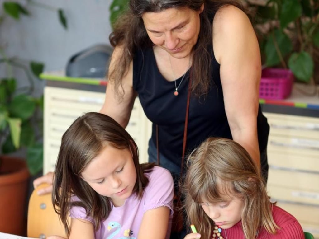 Die Freie Schule in Huntlosen ist für Luna (rechts) und Carlotta (links) Spiel- und Lernort zugleich. Schulleiterin Katharina Krebs (stehend) glaubt, dass Kinder aus freien Stücken heraus besser lernen. Foto: Markus Hibbeler