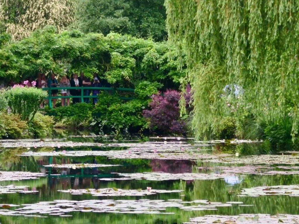 Touristenmagnet: Von einer kleinen Brücke aus schauen Besucher über einen Teich im Künstlergarten von Claude Monet. Foto: Daniela David