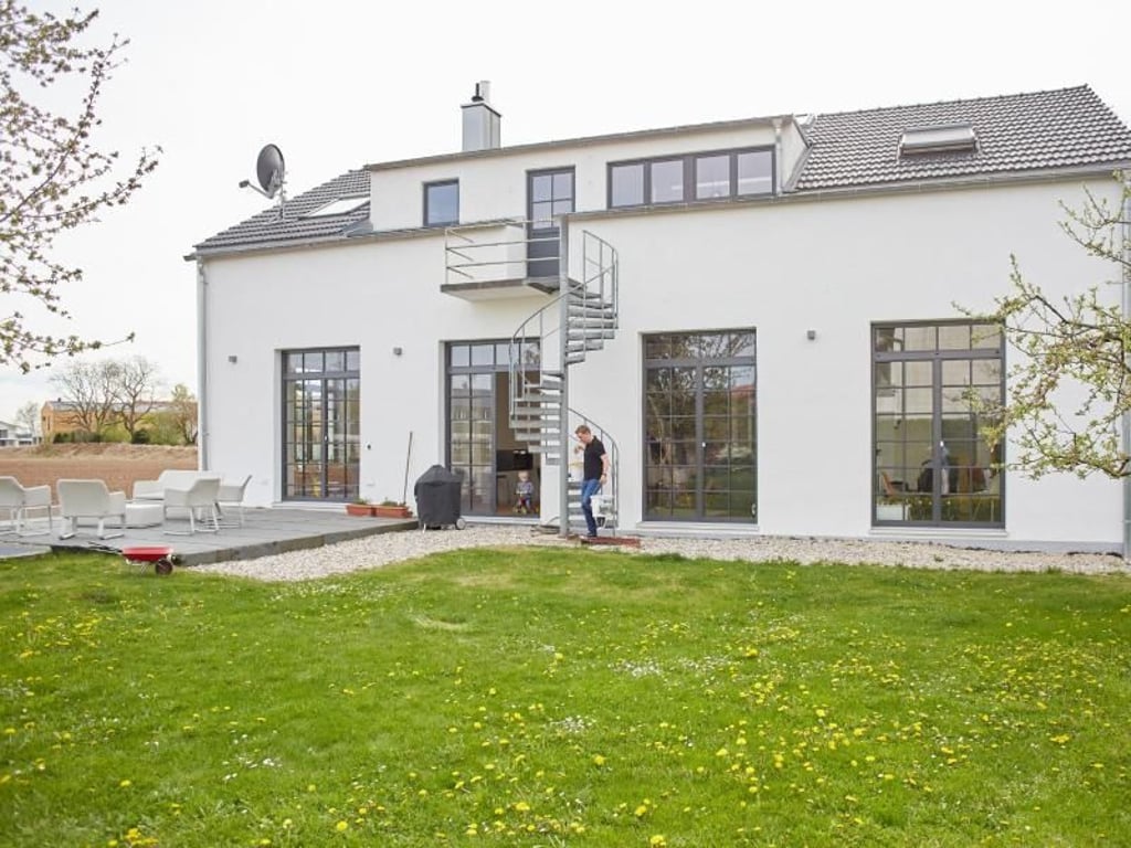 Große Fenster in Kassettenoptik bestimmten das Äußere der ehemaligen Autowerkstatt im bayerischen Parsdorf. Darin wohnt heute eine Familie mit zwei Kindern. Foto: KfW/Claus Morgenstern