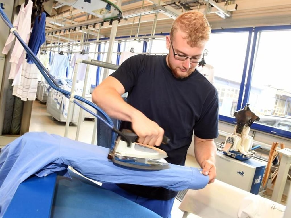 Auch das Bügeln gehört zu den Aufgaben von Andreas Wagner. Der 21-Jährige macht bei der Firma Bardusch in Ettlingen eine Ausbildung zum Textilreiniger. Foto: Uli Deck