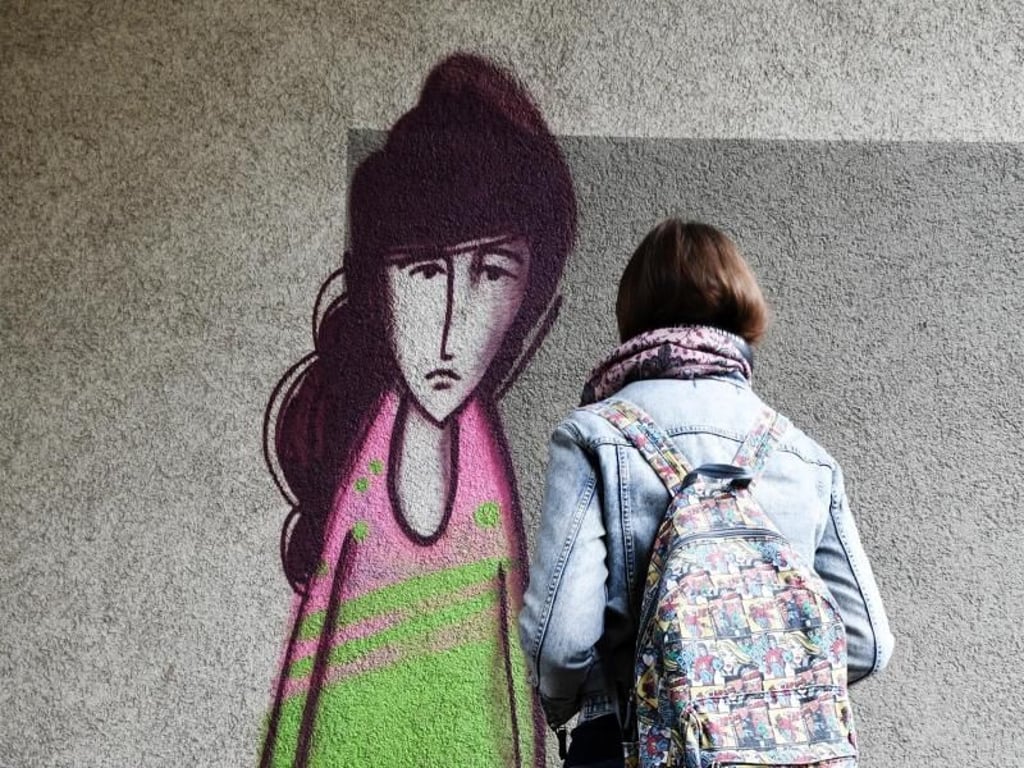 Eine Studentin in der Mainzer Neustadt die Streetart-Darstellung des "Traurigen Mädchens". Foto:Peter Zschunke