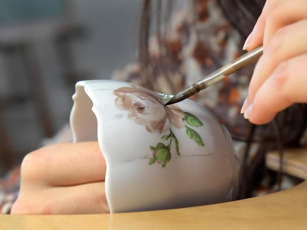 Ein filigranes Blumenmuster entsteht auf einer Tasse: Für ihre Arbeit brauchen angehende Manufakturporzellanmaler eine absolut ruhige Hand. Foto: Matthias Rietschel