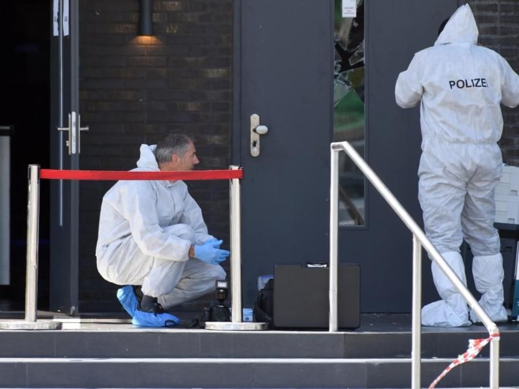 Zwei Polizisten in weißen Schutzanzügen sichern vor der Diskothek Spuren. Foto: Felix Kästle