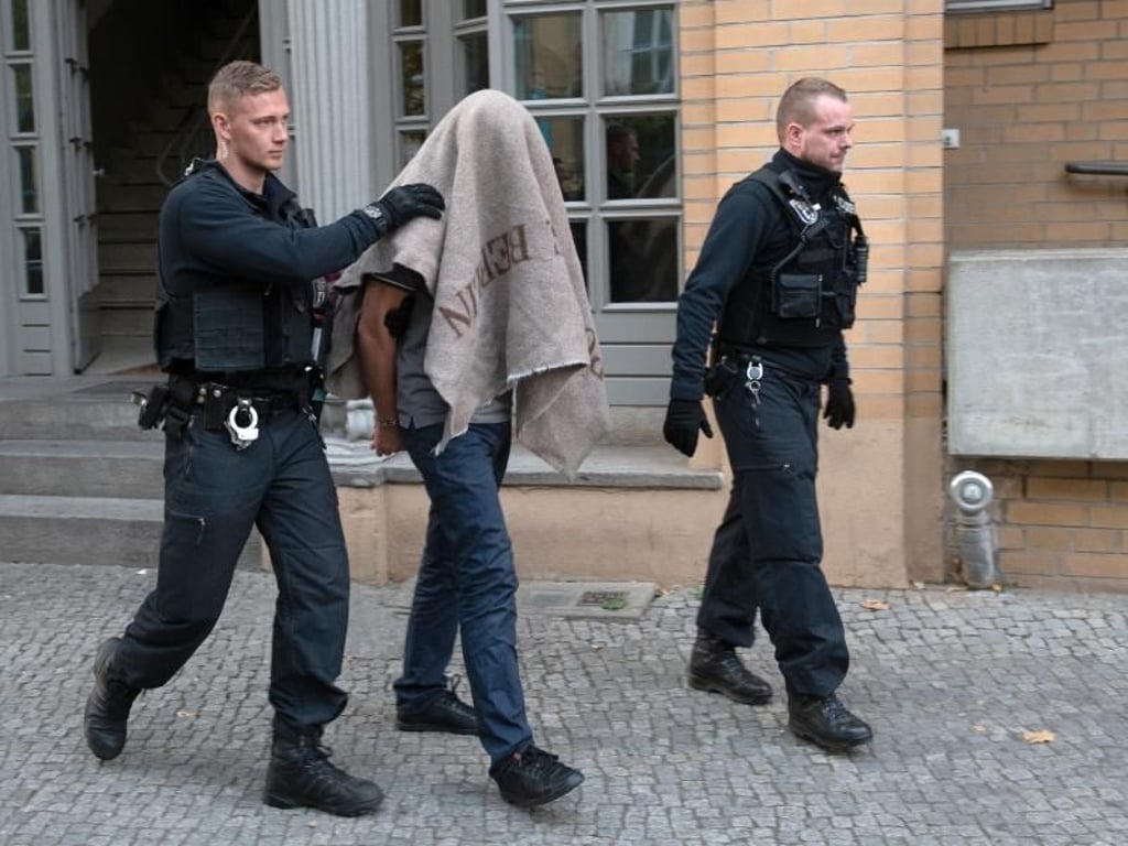 Polizisten führen einen verdächtigen Mann ab. Foto: Paul Zinken