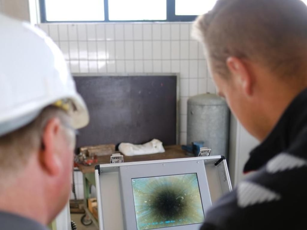 Mit Schulterblick: Lehrwerkmeister Lothar Schoka (links) und Azubi Philipp Mülder kontrollieren das Bild einer Brunnenkamera. Foto: Markus Hibbeler/dpa-tmn
