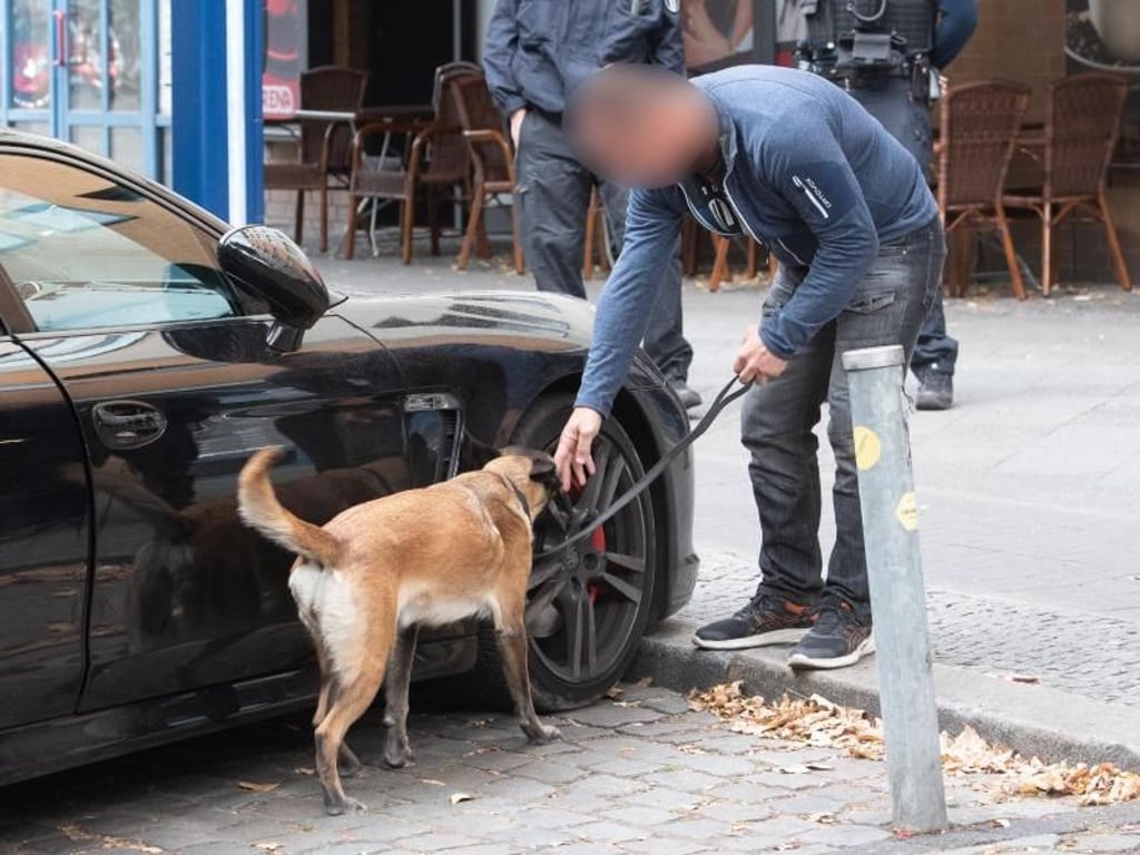 Ein Polizist untersucht mit einem Spürhund ein verdächtiges Fahrzeug. Foto: Paul Zinken