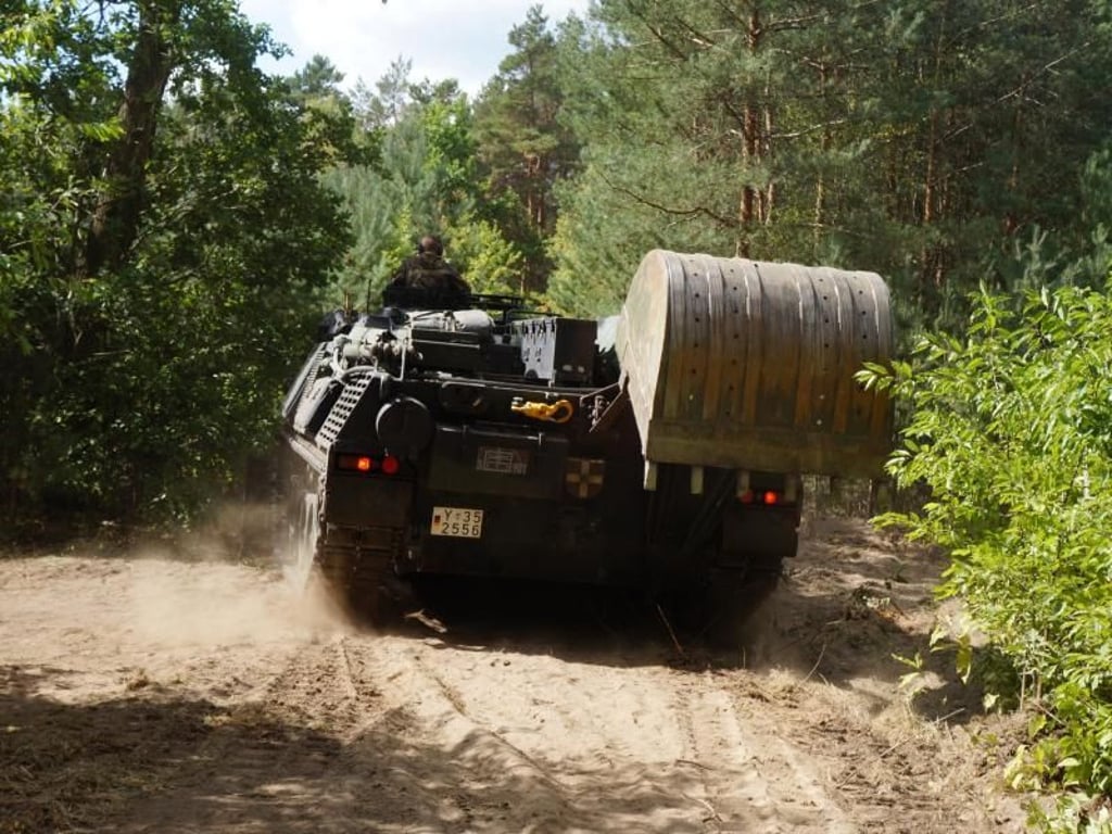 Ein Panzer der Bundeswehr schneidet eine Schneise in den Wald, damit die Feuerwehrleute besser an die Glutherde herankommen. Foto: Christian Pörschmann