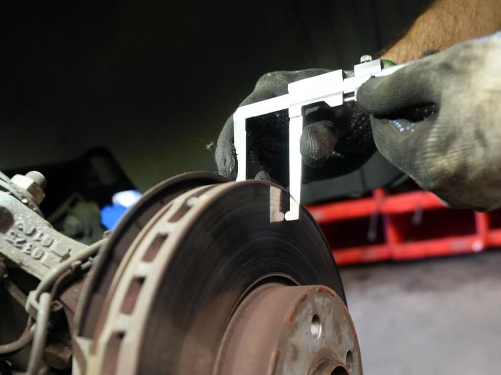 Ein Mitarbeiter prüft in der markenfreien Rheinlandgarage in Köln bei einer Inspektion die Dicke einer Bremsscheibe. Foto: Henning Kaiser