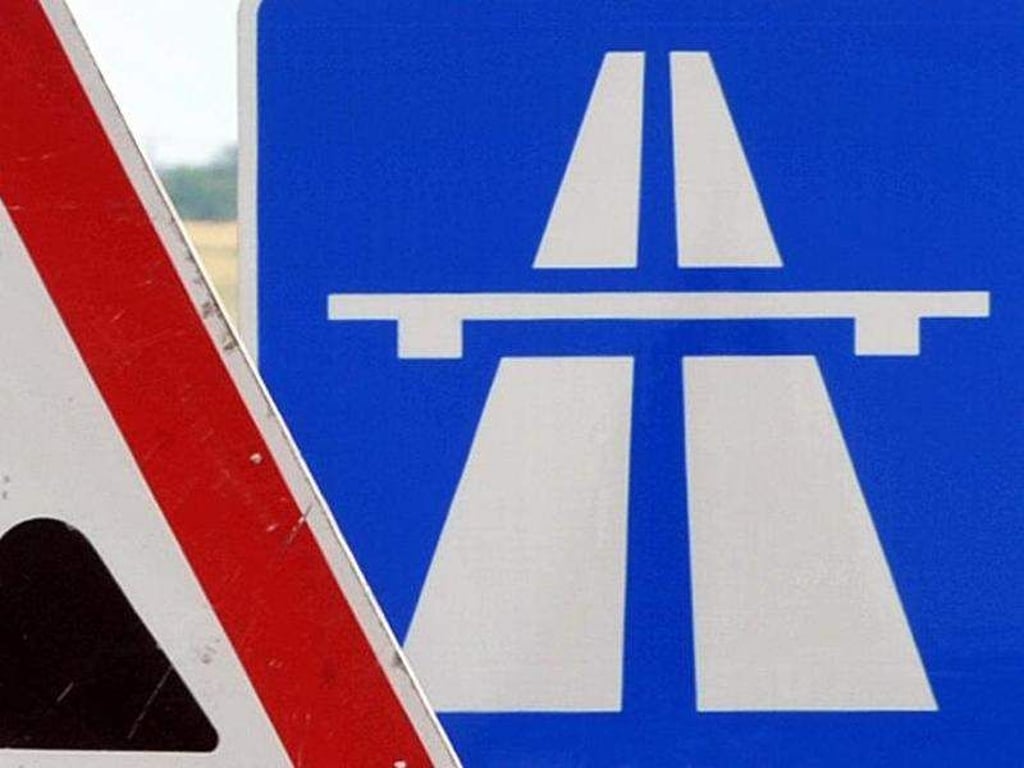 Ein Baustellenschild ist vor einem Autobahschild platziert. Foto: Martin Schutt/Archiv