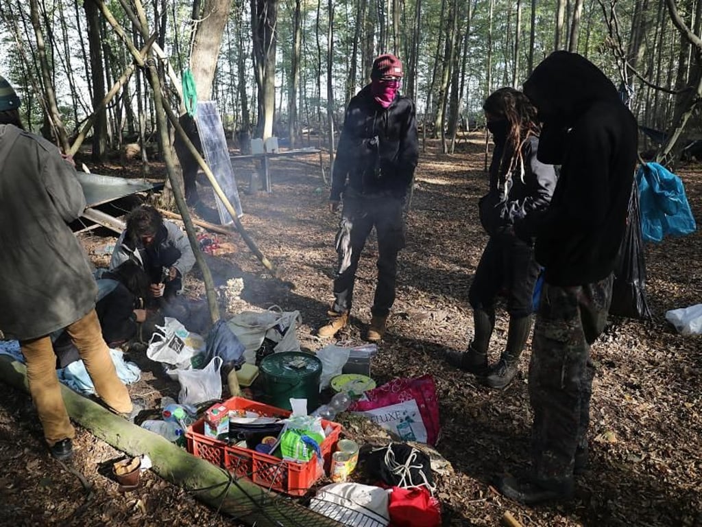 Aktivisten stehen im Hambacher Forst an einer Feuerstelle. Foto: Oliver Berg