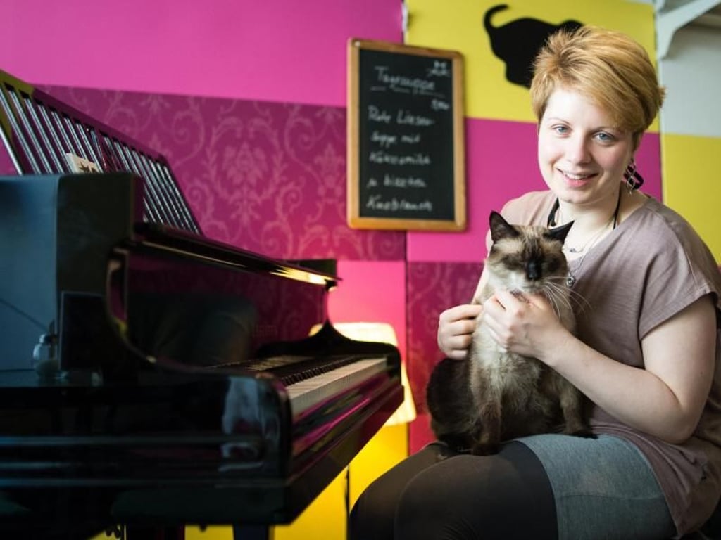 Café-Besitzerin Caroline Braune mit Kater Jackey-Smokey: Zum Konzept von «Zur Mieze» gehört auch die Verbindung mit Musik. Einmal pro Woche spielt ein Pianist ein klassisches Konzert. Foto:Franziska Gabbert/dpa-tmn