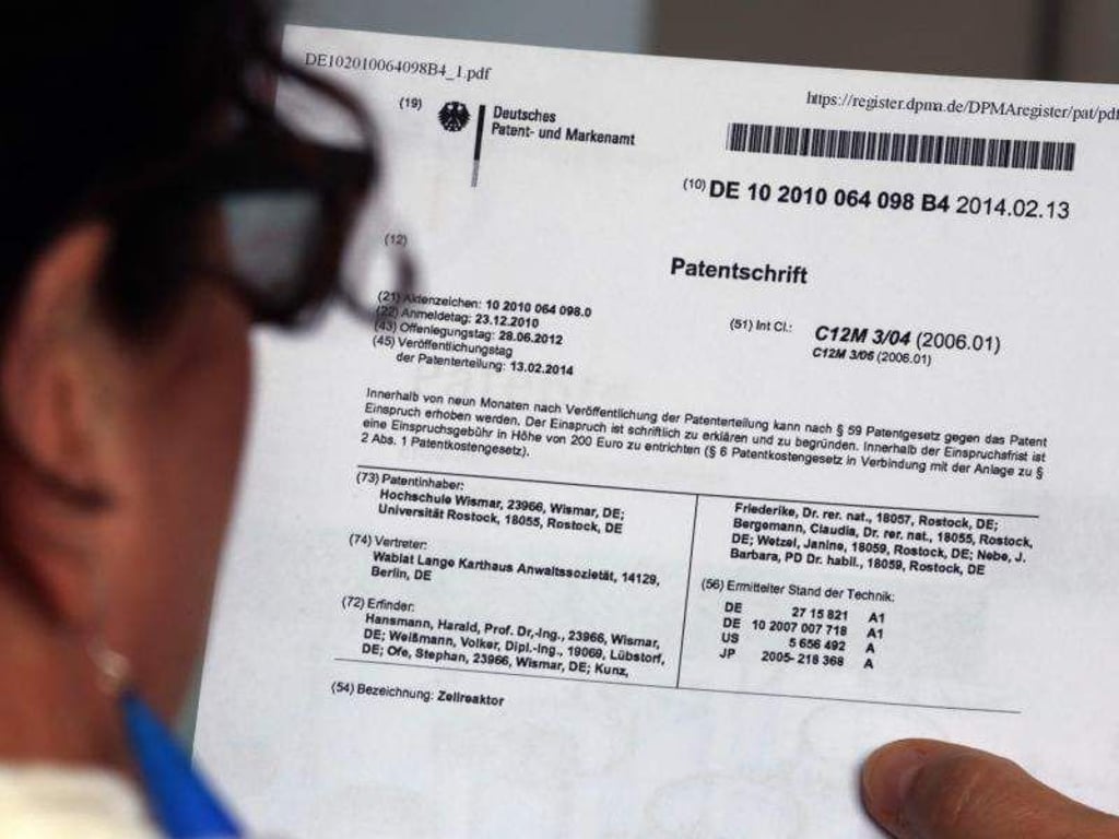 Eine Frau hält eine Patentschrift in der Hand. Foto: Bernd Wüstneck/Archiv