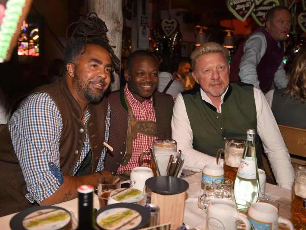 Der ehemalige Fußballer Patrick Owomoyela (l-r), Raphael de Souza und Boris Becker feiern beim Almauftrieb im Käferzelt. Foto: Felix Hörhager