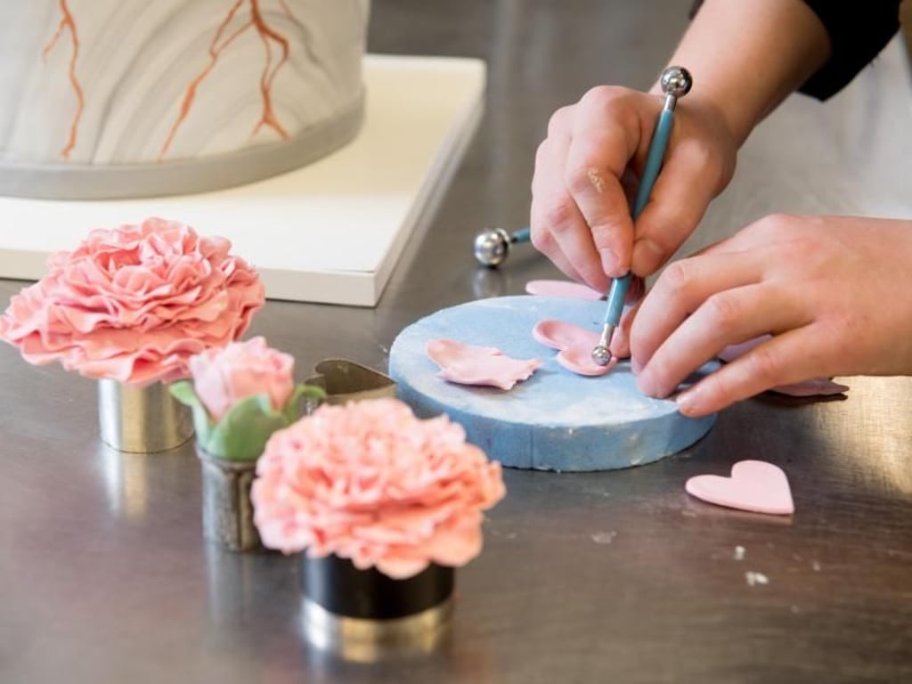 Eine kreative Ader und ästhetisches Empfinden sind Voraussetzungen: Mit raffinierten Rosenblättern aus Modellierschokolade wird etwa eine Hochzeitstorte zum Blickfang. Foto: Tobias Hase