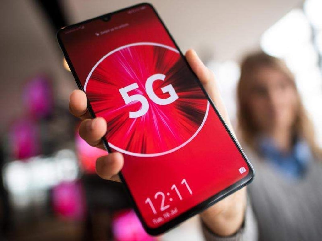Eine Vodafone-Mitarbeiterin hält ein 5G-Smartphone in der Hand. Foto: Federico Gambarini/Archiv