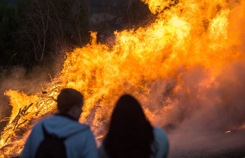 21.04.2019, Nordrhein-Westfalen, Lügde: Zuschauer stehen vor einem Osterfeuer am Rande des Osterräderlaufes. Bei dem Osterritual werden in Lügde seit vielen Generationen brennende Holzräder von Hügeln gerollt. Seit Dezember 2018 ist die Tradition als deutsches immaterielles Kulturerbe der Unesco gelistet. Foto: Caroline Seidel/dpa +++ dpa-Bildfunk +++