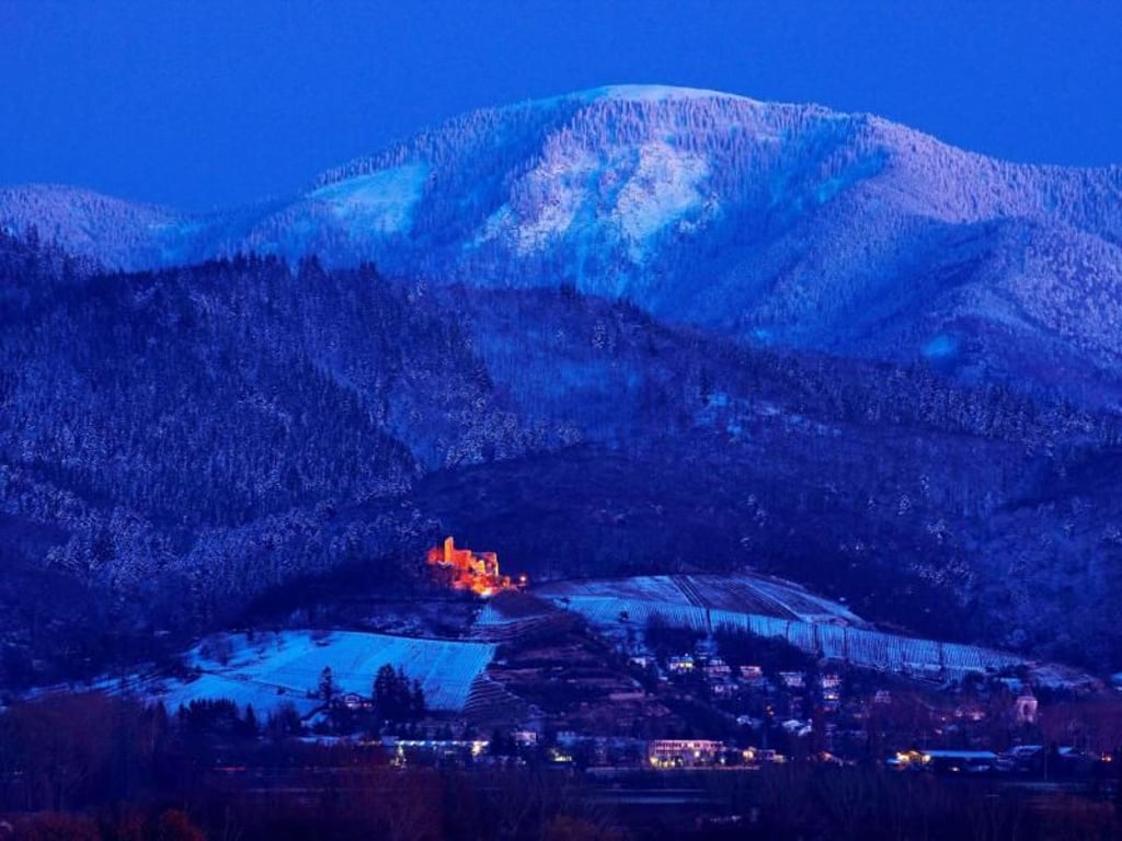 Die Staufener Burgruine leuchtet in der Nacht, inmitten einer leicht gezuckerten Winterlandschaft. Foto: Ferienregion Münstertal Staufen/Erich Spiegelhalter