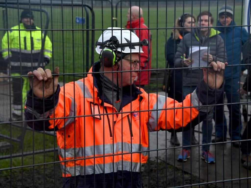 Ein Arbeiter hält ein Zaunelement auf der Baustelle des Wildschweinzaunes. Foto: Carsten Rehder