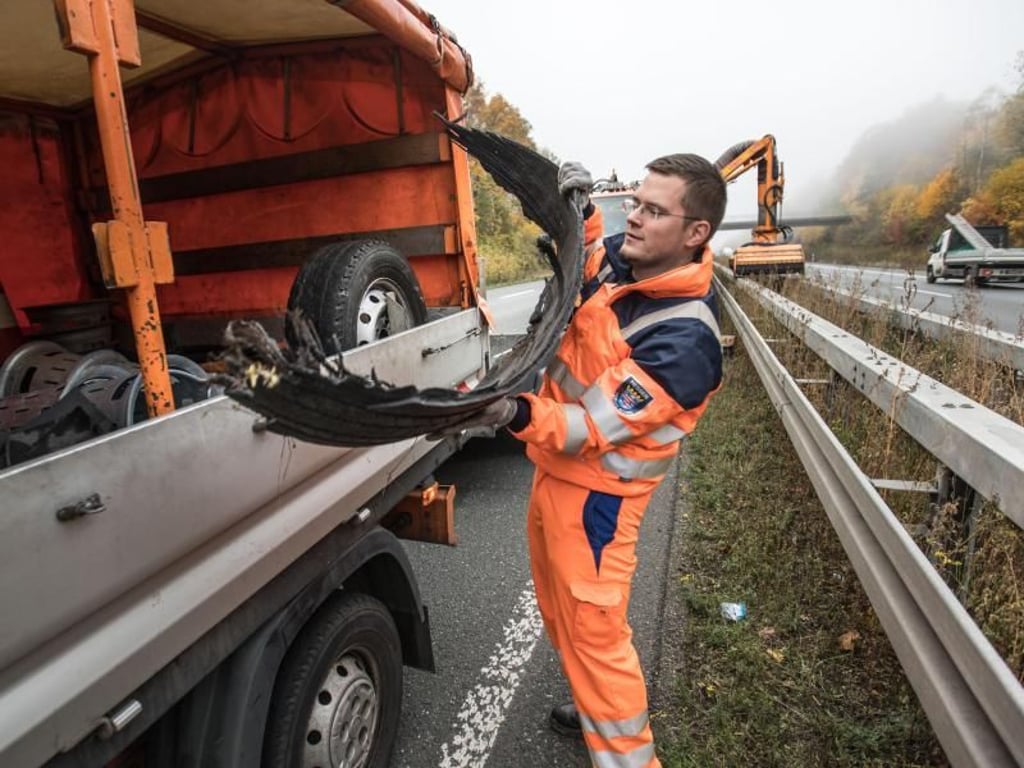 Zutz lädt auf der abgesperrten Überholspur der A485 eine Lauffläche eines LKW-Reifens auf seinen Wagen. Er hat sie auf dem Mittelstreifen gefunden. Foto: Frank Rumpenhorst