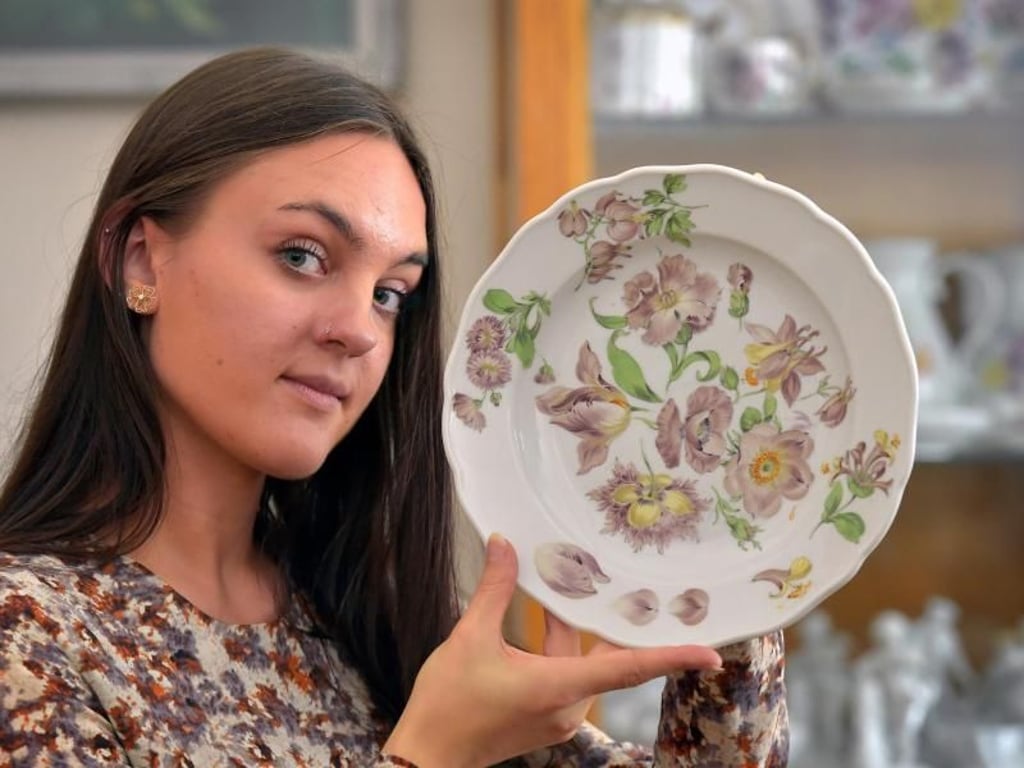 Das Malen nach der Natur, wie diese Blüten, lernen angehende Manufakturporzellanmaler wie Lucinde Friedrich am Anfang ihrer Ausbildung. Hier präsentiert sie einen fertigen Teller. Foto: Matthias Rietschel