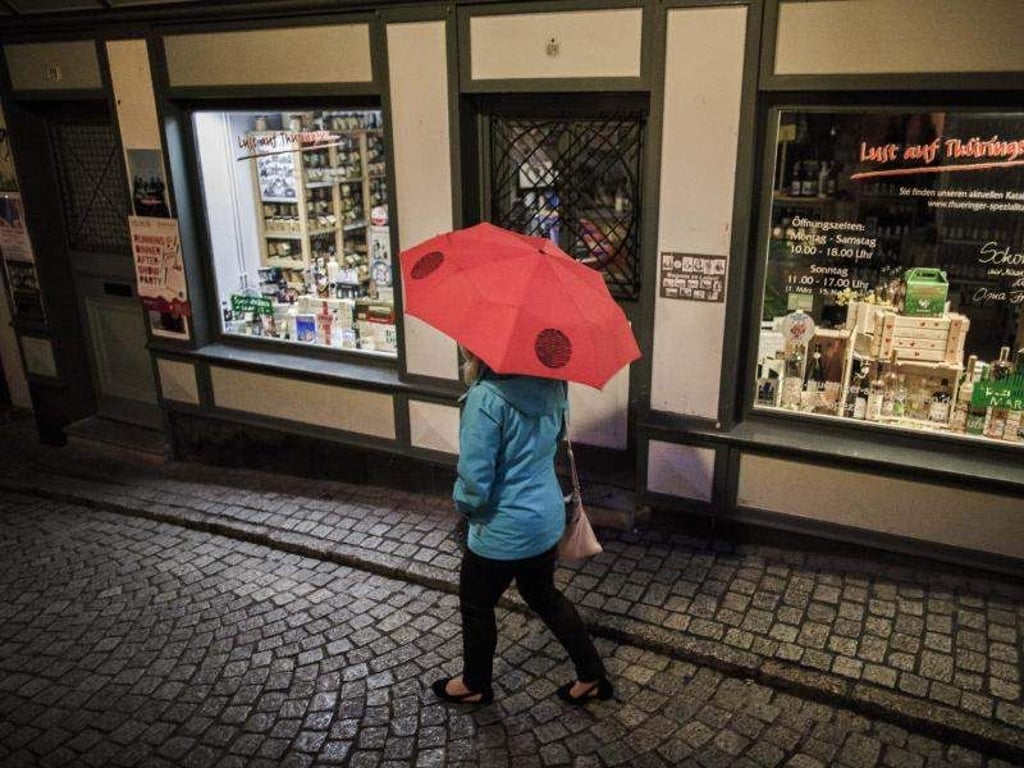 Eine Frau schützt sich mit einem Regenschirm vor dem Regen auf der Krämerbrücke. Foto: Carsten Koall/Archiv
