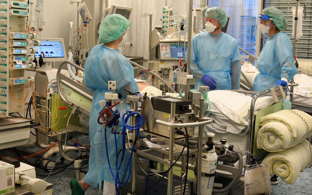Ein Arzt und zwei Pflegerinnen versorgen einen Patienten auf einer Intensivstation.
