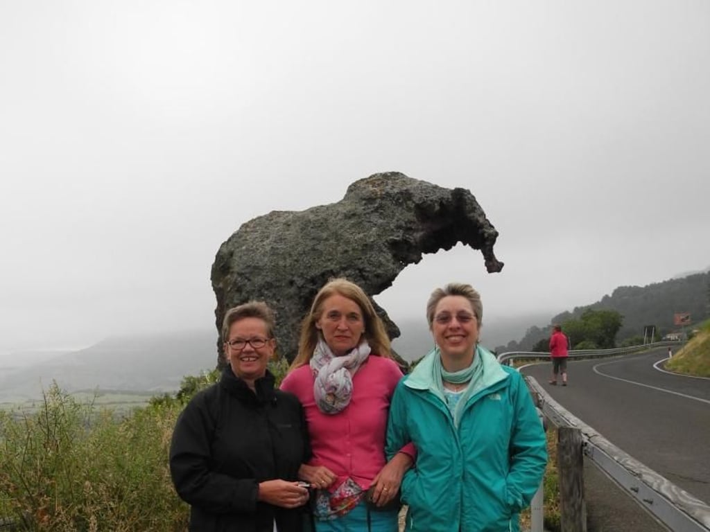 Schlechtes Wetter, aber gute Stimmung (l-r): Marita, Trauerbegleiterin Regina und Helga posieren vor dem Elefantenfels. Der Steinbrocken ist eine der Sehenswürdigkeiten auf Sardinien. Foto: Kristin Kruthaup