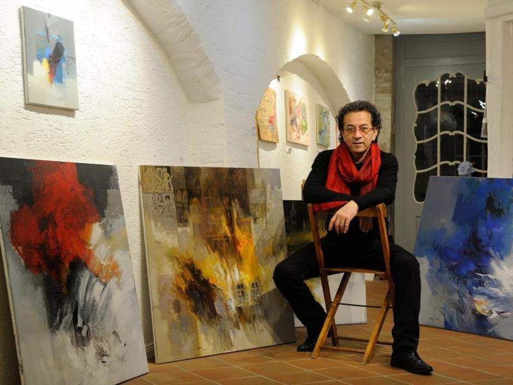 Der syrische Künstler Naser Nassan Agha zwischen einigen seiner Bilder in der Galerie ART15 in Bremen. Foto: Ingo Wagner