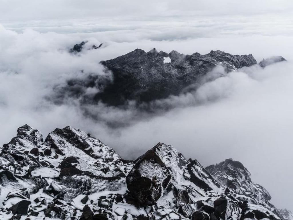 Auf dem Margherita-Gipfel reißt der Himmel etwas auf und gibt den Blick frei auf die wolkenverhangenen und verschneiten Berge der Umgebung. Foto: Philipp Laage