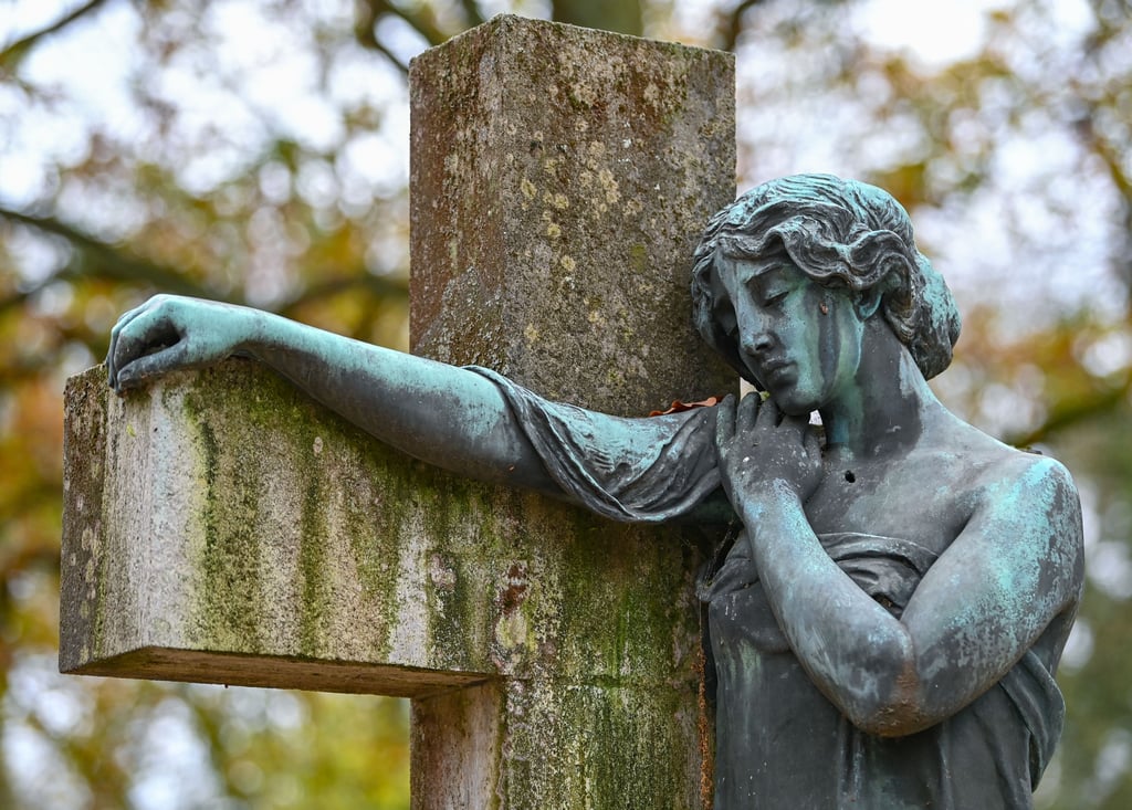 Eine Bronzefigur in Form eines Engels an einem Kreuz auf einem Friedhof. Mit einer zweistündigen Debatte beginnt der Bundestag Beratungen über neue Regeln für die Sterbehilfe. Die alten hat das Bundesverfassungsgericht für nichtig erklärt.