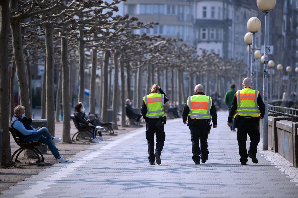 Mitarbeiter des Ordnungsamtes gehen in Düsseldorf am Rheinufer entlang, um die Maskenpflicht zu überprüfen.
