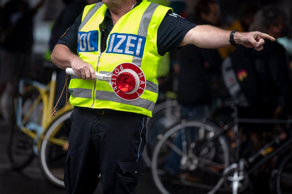 Ein Polizist gibt mit der roten Kelle Anweisungen.