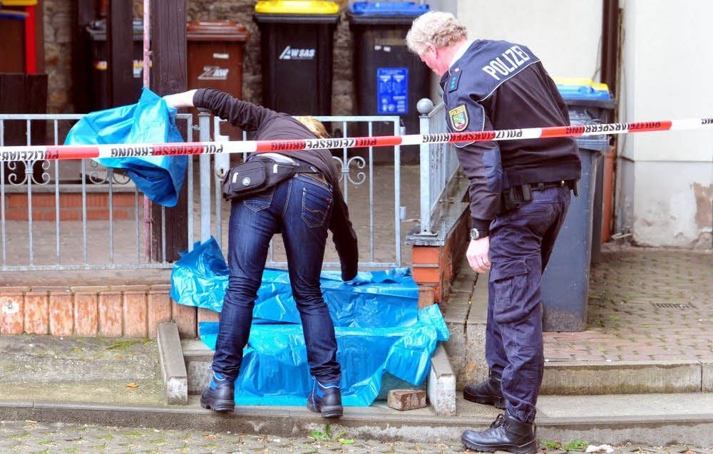 Polizisten decken Spuren mit Planen ab, damit sie nicht vom Regen verwischt werden.