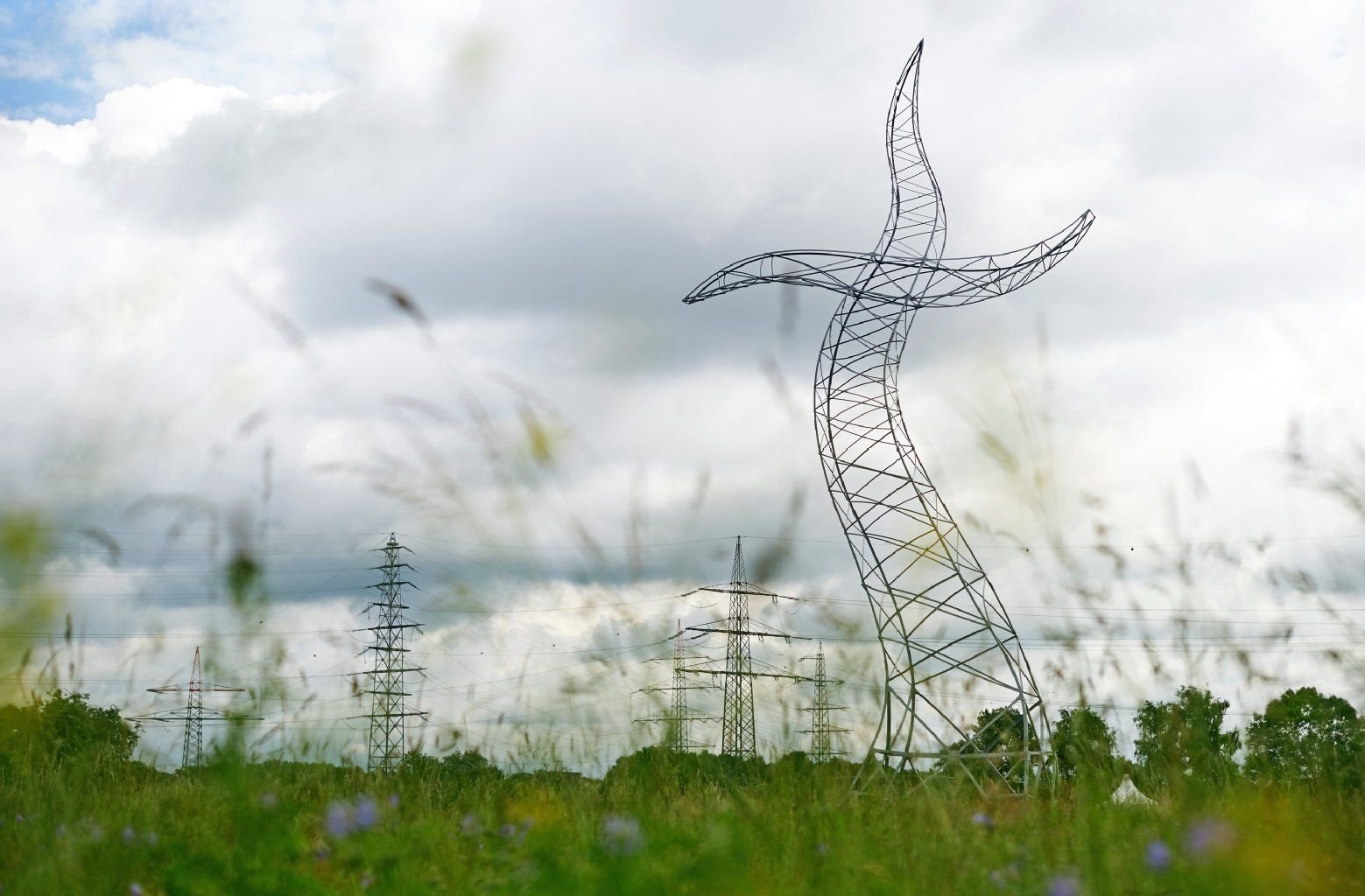 Die Großskulptur «Der Zauberlehrling» der Künstlergruppe Inges Idee aus Berlin steht in Oberhausen auf einer Wiese vor Strommasten.