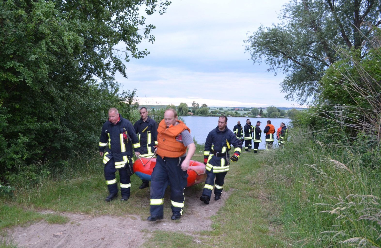 Kameraden der Feuerwehr tragen ein Schlauchboot. Am Samstag wurde auch auf dem Süßen See nach der vermissten 46-Jährigen gesucht.