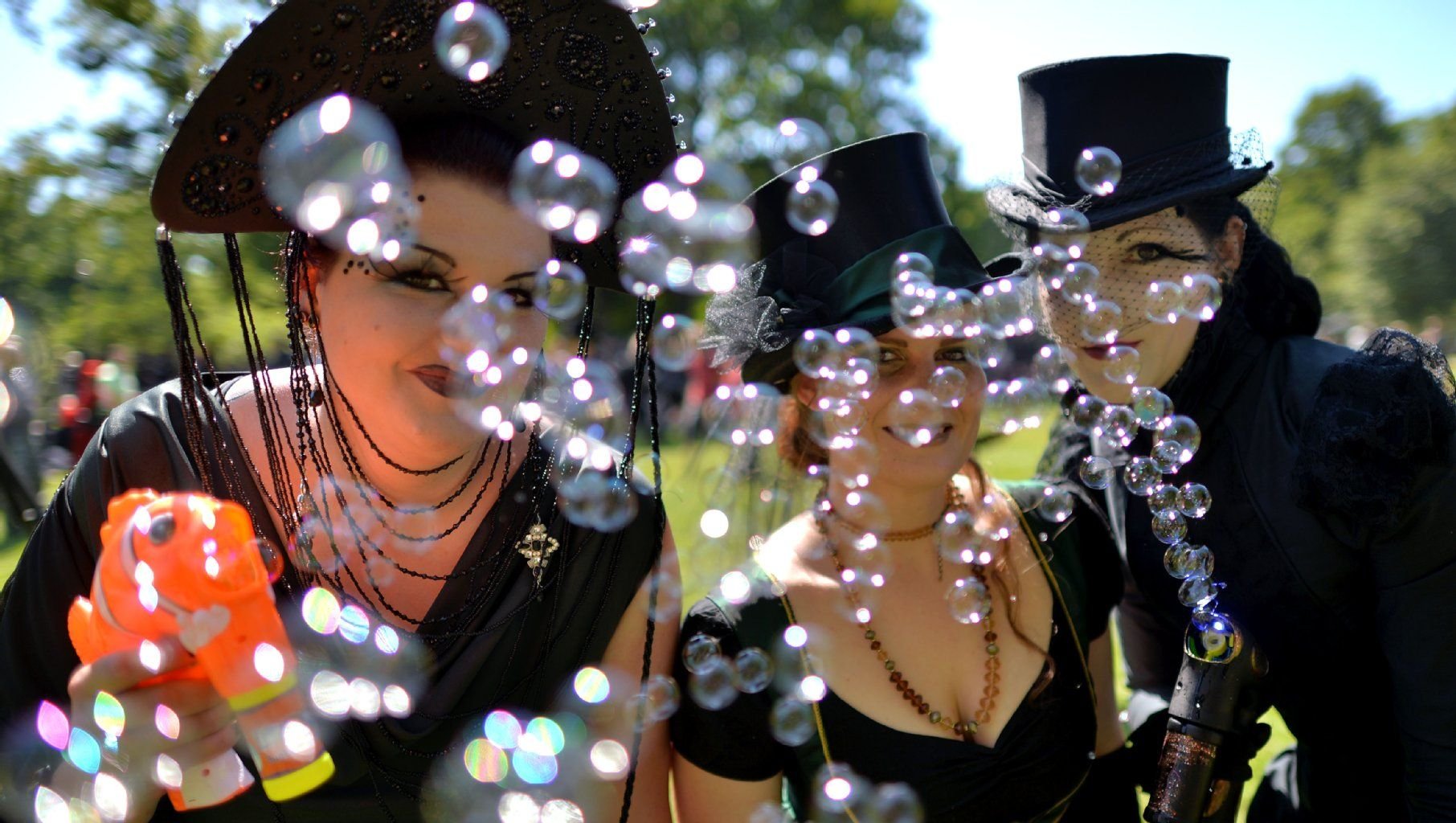 In ihren viktorianischen Kostümen erfreuen sich Katrin, Solveig und Anna (v.l.) am 06.06.2014 auf dem Wave-Gotik-Treffen in einem Park in Leipzig (Sachsen) an ihren Seifenblasen.