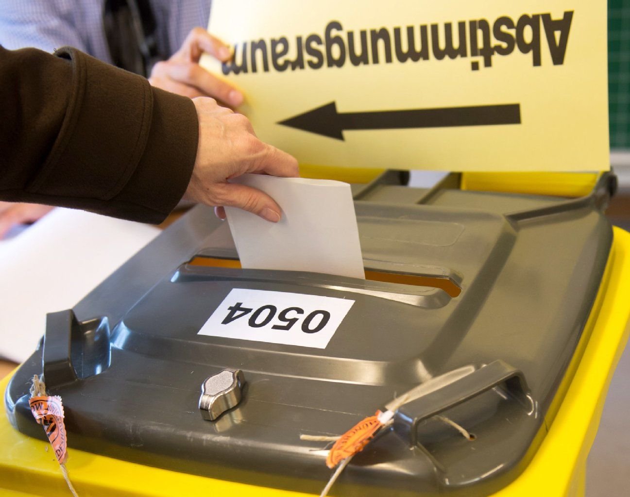 Eine Frau wirft in München ihren Stimmzettel für den Bürgerentscheid in eine gelbe Wahlurne.