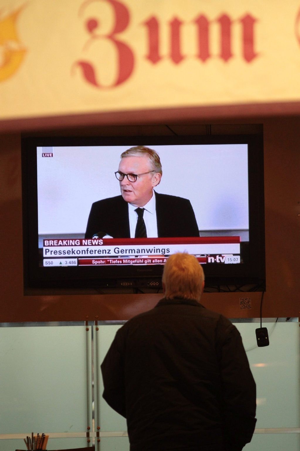 Ein Mann verfolgt die Pressekonferenz von Germanwings und erhofft sich Neuigkeiten.