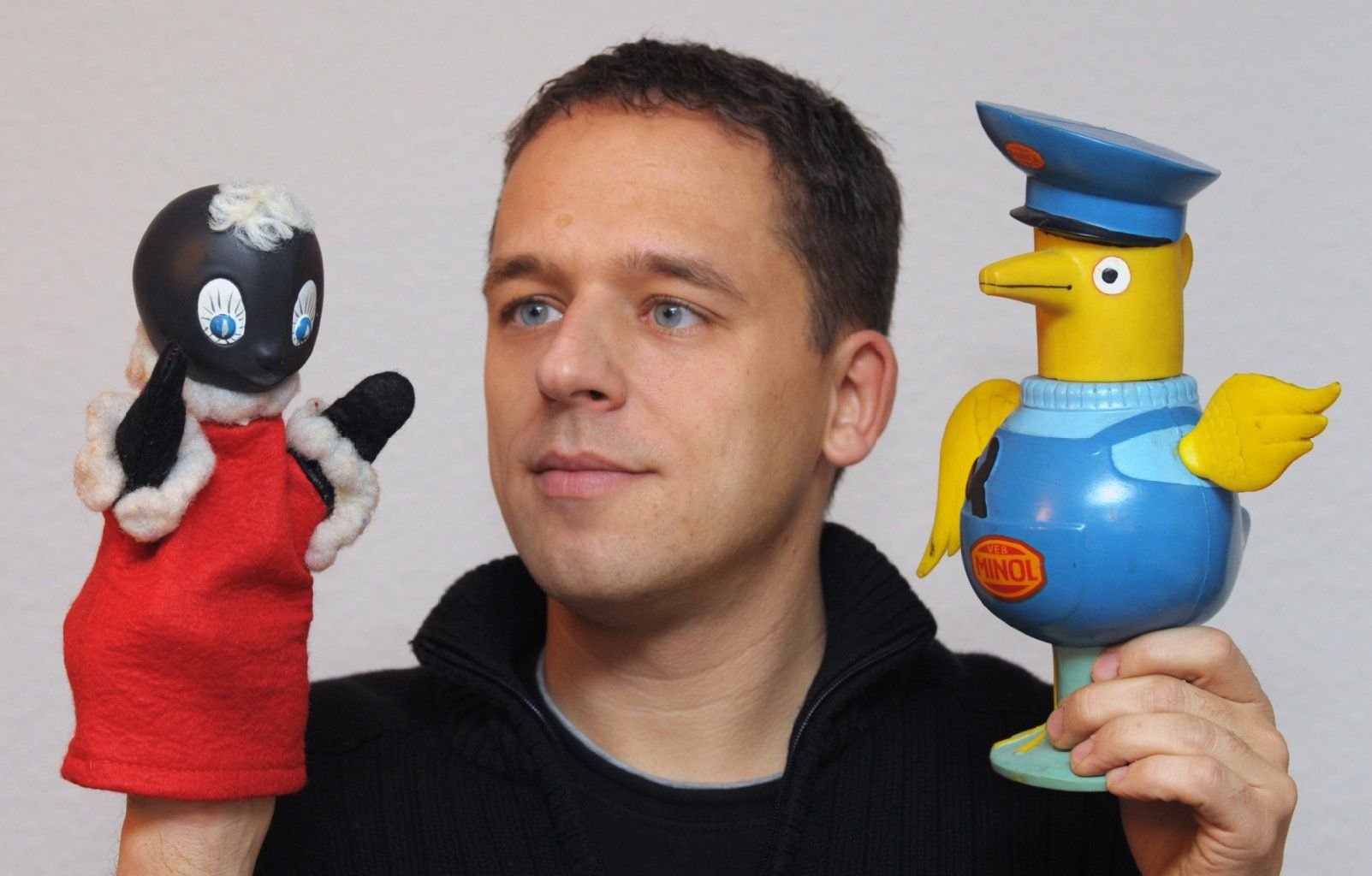 Der Spielzeugsammler Eric Palitzsch mit dem Maskottchen der ehemaligen DDR-Tankstellenkette "Minol", dem "Minolpirol" (r.) und der beliebten Figur "Pittiplatsch" vom DDR-Kinderfernsehen.
