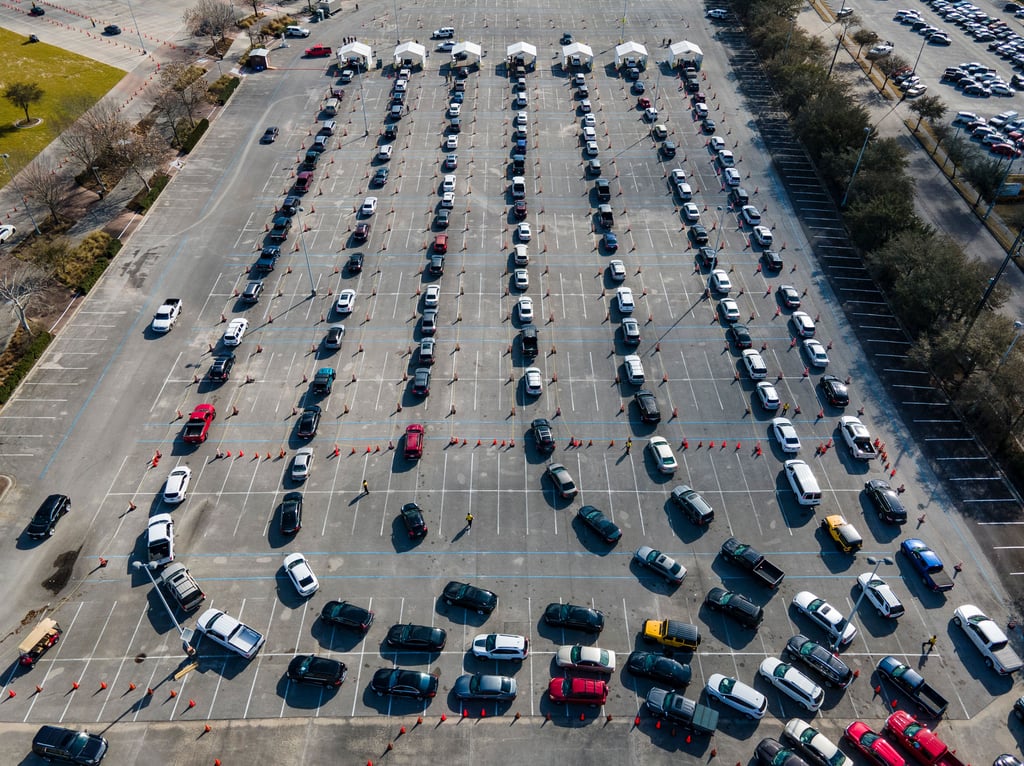 USA, Houston: Autos stehen auf einem Parkplatz am NRG Park in einer Schlange, während die Fahrer darauf warten, gegen das Coronavirus geimpft zu werden.