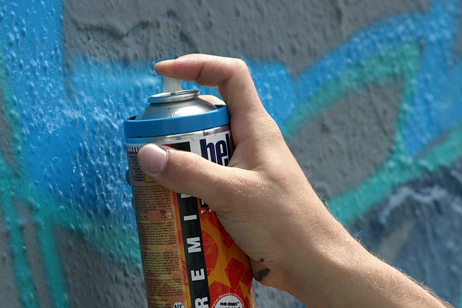 Ein Graffiti-Sprayer besprüht eine Mauer.