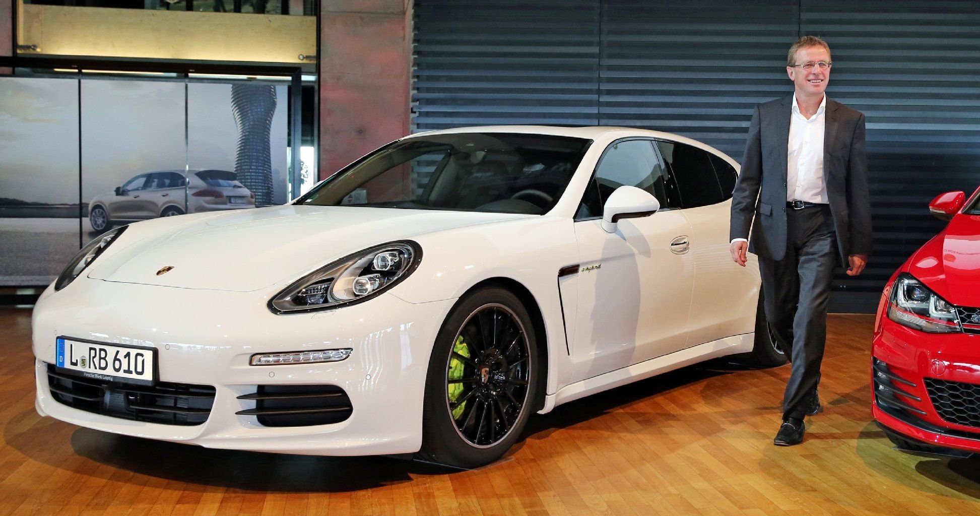RB-Sportdirektor Ralf Rangnick geht zwischen einem Porsche Panamera Hybrid und einem Golf GTI am Rande eines Pressetermins im Kundenzentrum des Porsche Werks Leipzig entlang.