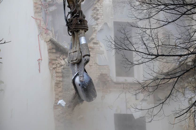 Mit dem Abrissgreifer wird eine Badewanne aus der Ruine gehoben.