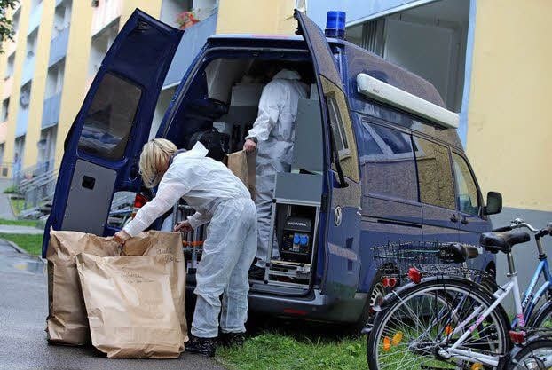 Nach dem Doppelmord sichern Kriminalbeamte Tüten mit Beweismitteln aus der Wohnung in einem Bitterfelder Neubaublock.