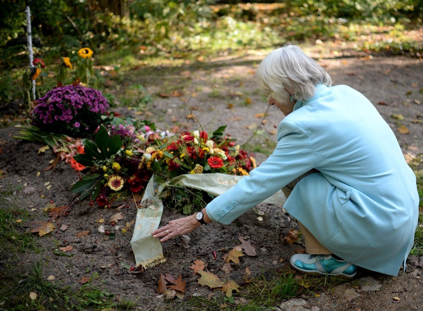 Astrid Osterland kniet auf dem Georgen-Parochial-Friedhof I in Berlin an einem Grab.