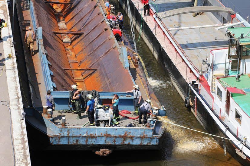 Ein Motorschiff (rechts) bringt das lecke Schiff zum Kai.