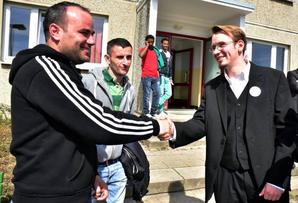 Pfarrer Johannes Rohr begrüßt Azem Sylejmani und Sabri Hasani aus dem Kosovo (von rechts).
