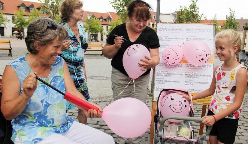 Die Mitglieder der Bürgerinitiative „Keine Schweinerei“, Hannelore Nickel (von links), Ilse Reichmann und Angelika Böhlk, warben am Samstag auf dem Bernburger Karlsplatz noch einmal für ihre Ziele und legten Emily Schütze einen Schweinchen-Luftballon in den Kinderwagen.
