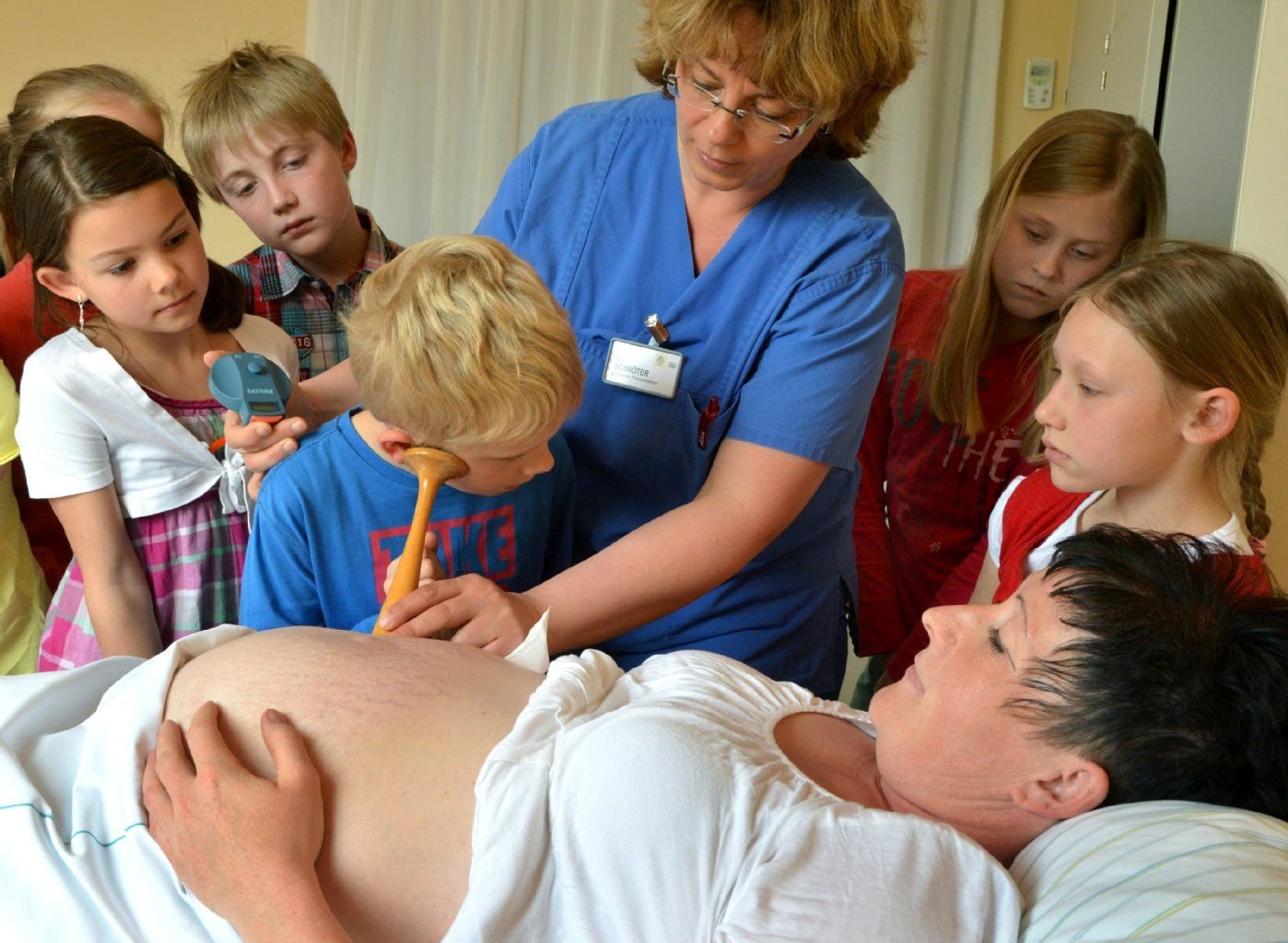 Schüler einer 3. Klasse der Grundschule Halle-Kröllwitz hören mit einem früher üblichen Holzstethoskop die Herztöne eines heranwachsendes Babys